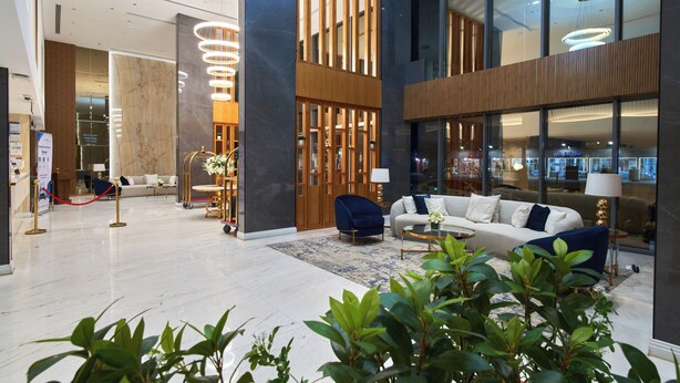Un lobby moderno con mostrador de recepción, zona de estar y un amplio ventanal.