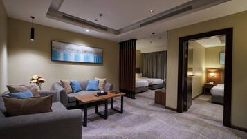 Una habitación de hotel con sofá, mesa, cama y espejo.