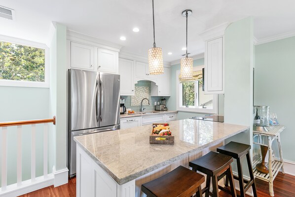 A modern kitchen with white cabinets, stainless steel appliances, and a central island with stools. - Updated villa on golf course, 3 min to beach! (Kiawah Island)