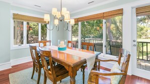 A dining area with a wooden table, chairs, and a chandelier. - Updated villa on golf course, 3 min to beach! (Kiawah Island)