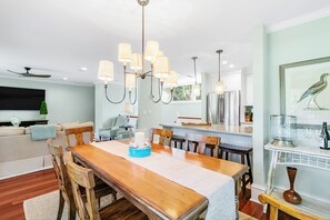 A dining area with a wooden table, chairs, and a chandelier. - Updated villa on golf course, 3 min to beach! (Kiawah Island)