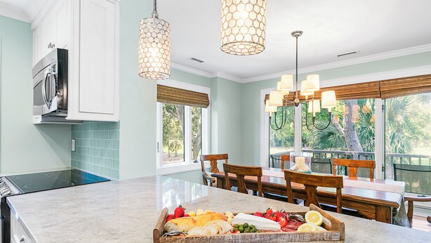 A kitchen with a marble countertop, wooden chairs, and a dining table. - Updated villa on golf course, 3 min to beach! (Kiawah Island)