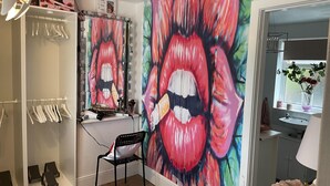 A room with a large mirror, a vanity with makeup items, a chair, and a colorful artwork of lips. - Immaculate 3-bed House in Bridgnorth (Bridgnorth)