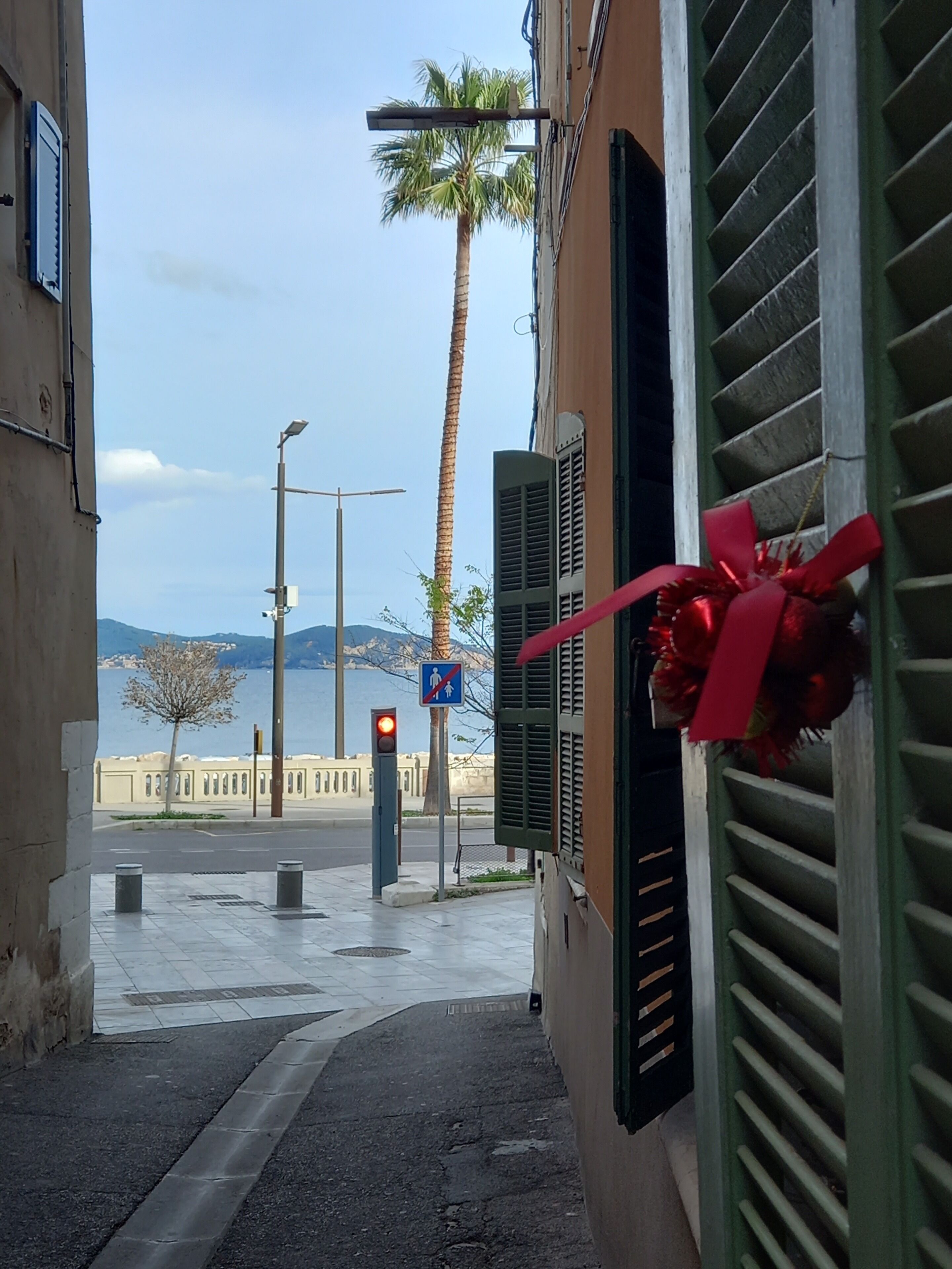 A narrow street with a view of the sea and mountains.