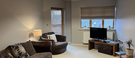 Een moderne woonkamer met een bank, een televisie en een lamp.