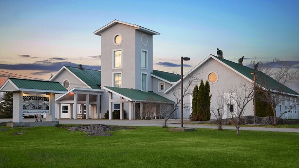 A modern building with a prominent tower, a covered entrance, and a sign for 'Prospectors Inn'. - Prospectors Inn (Kirkland Lake)