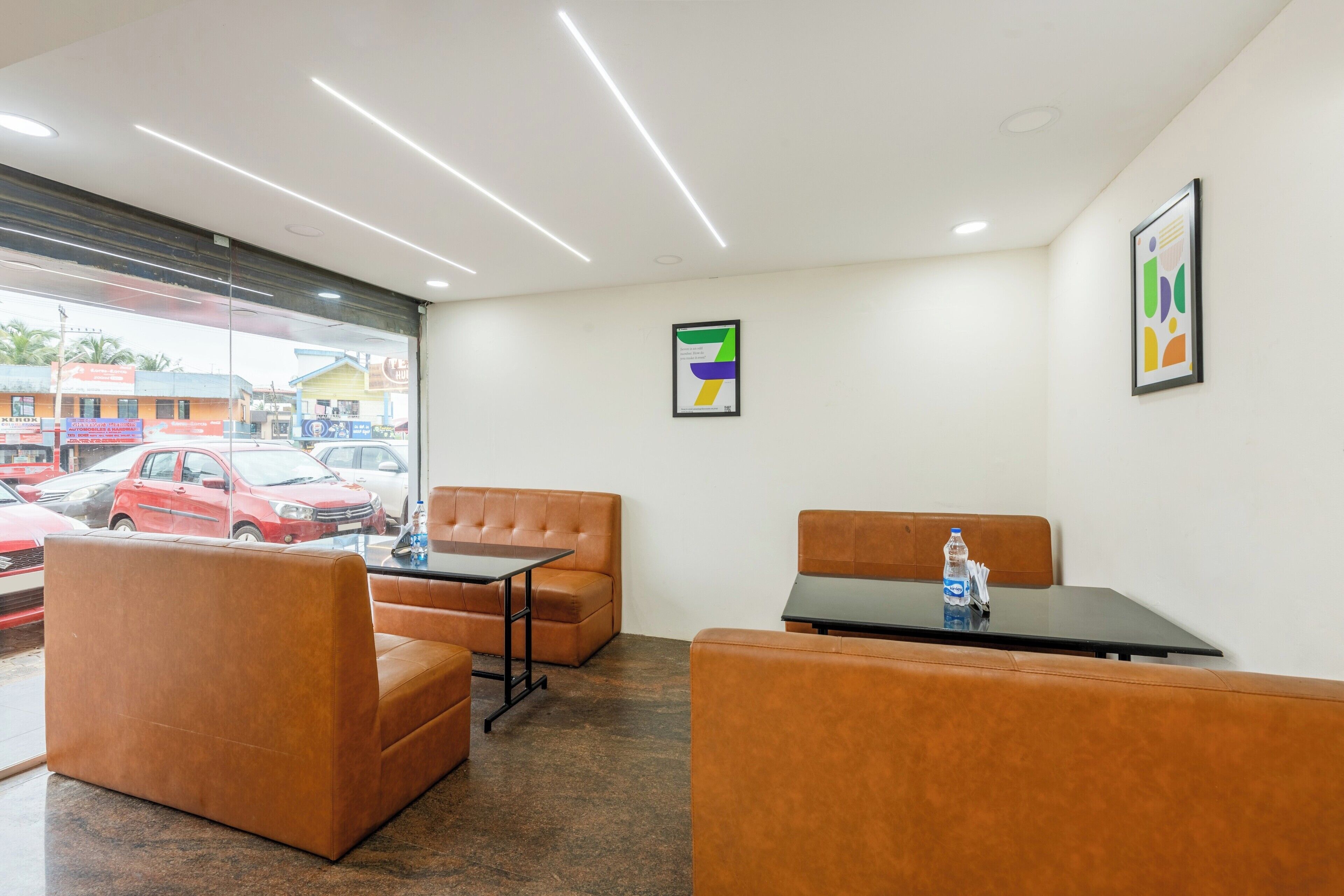 A hotel room with a large window, a sofa, a table, and a water bottle on the table.