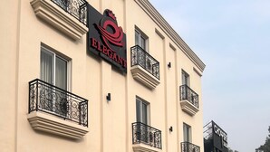 A building with balconies, a sign for 'ELEGANT Executive Suites,' and a parked car. - Hotel Elegant Executive Suites (Multan)