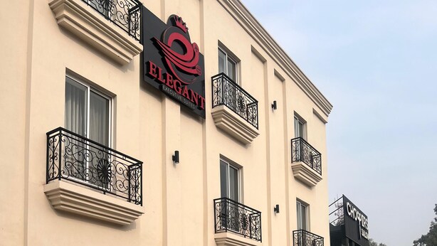A building with balconies, a sign for 'ELEGANT Executive Suites,' and a parked car. - Hotel Elegant Executive Suites (Multan)