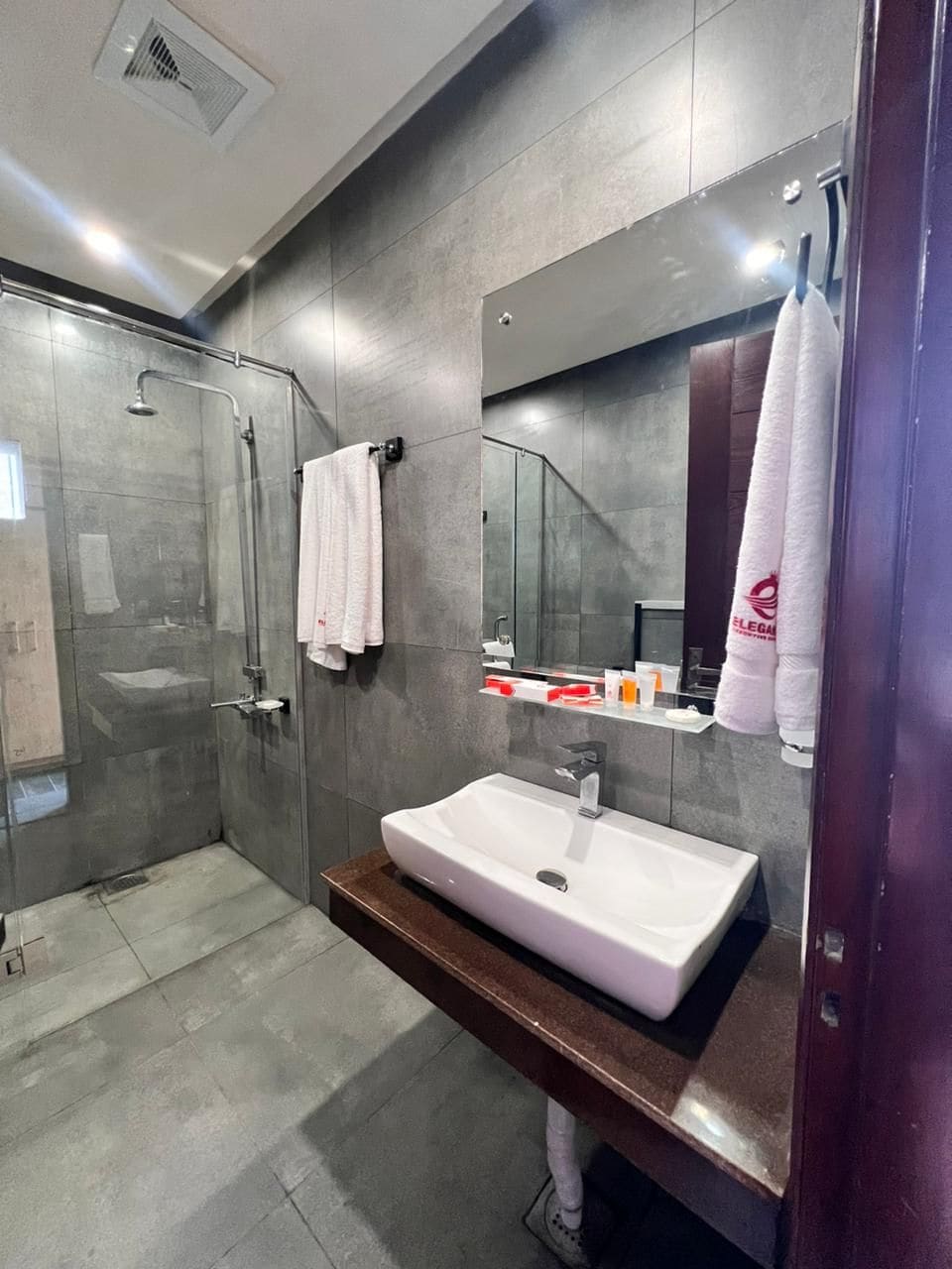 Une salle de bain moderne avec une douche à parois de verre, un lavabo blanc et un miroir au-dessus.