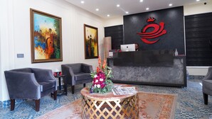 A reception area with a desk, chairs, artwork, and a patterned carpet. - Hotel Elegant Executive Suites (Multan)