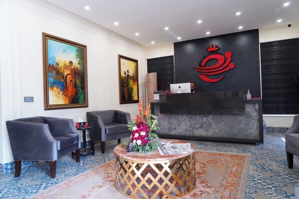 A reception area with a desk, chairs, artwork, and a patterned carpet. - Hotel Elegant Executive Suites (Multan)