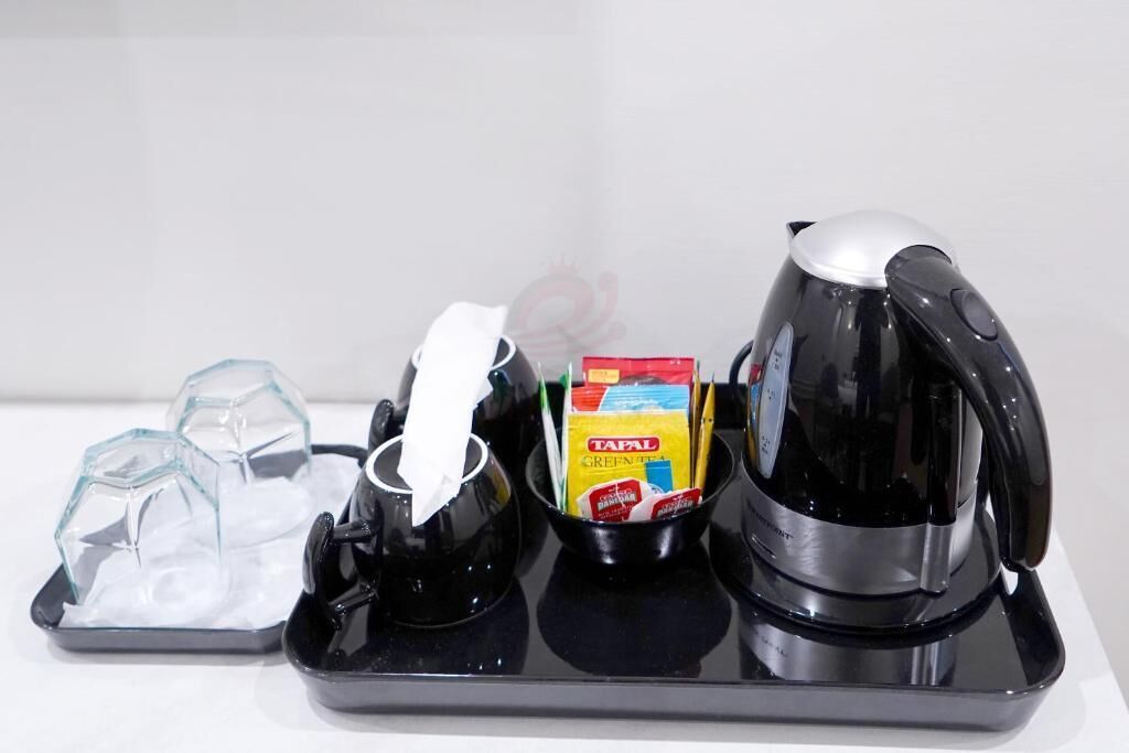 Una bandeja negra con una cafetera, un recipiente de vidrio y una caja de Té Verde Tafel.