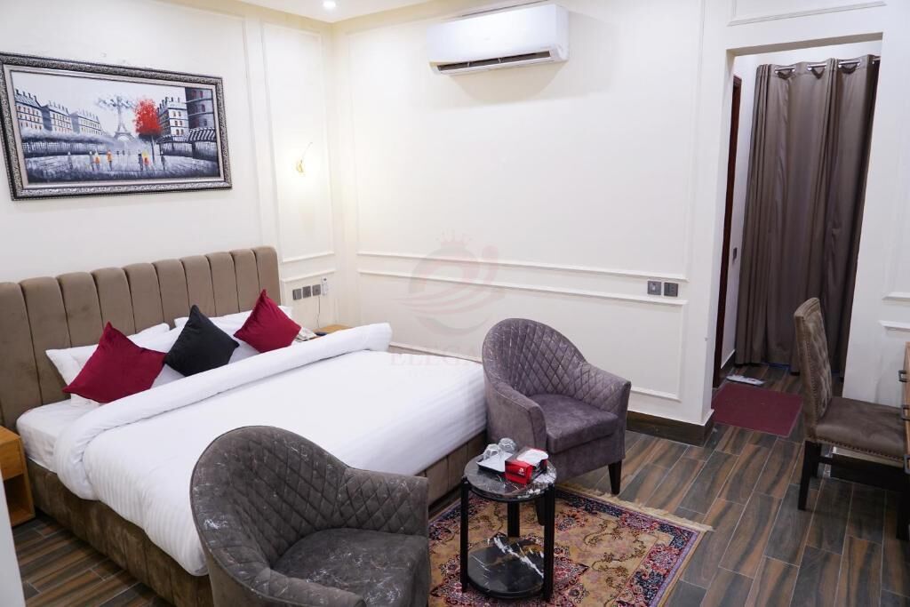 Une chambre d’hôtel avec un lit, deux fauteuils, une petite table et un tapis.