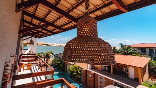 A hanging lamp with a woven design, a pool, and a view of the sea. - POUSADA SOLLARI (Trairi)