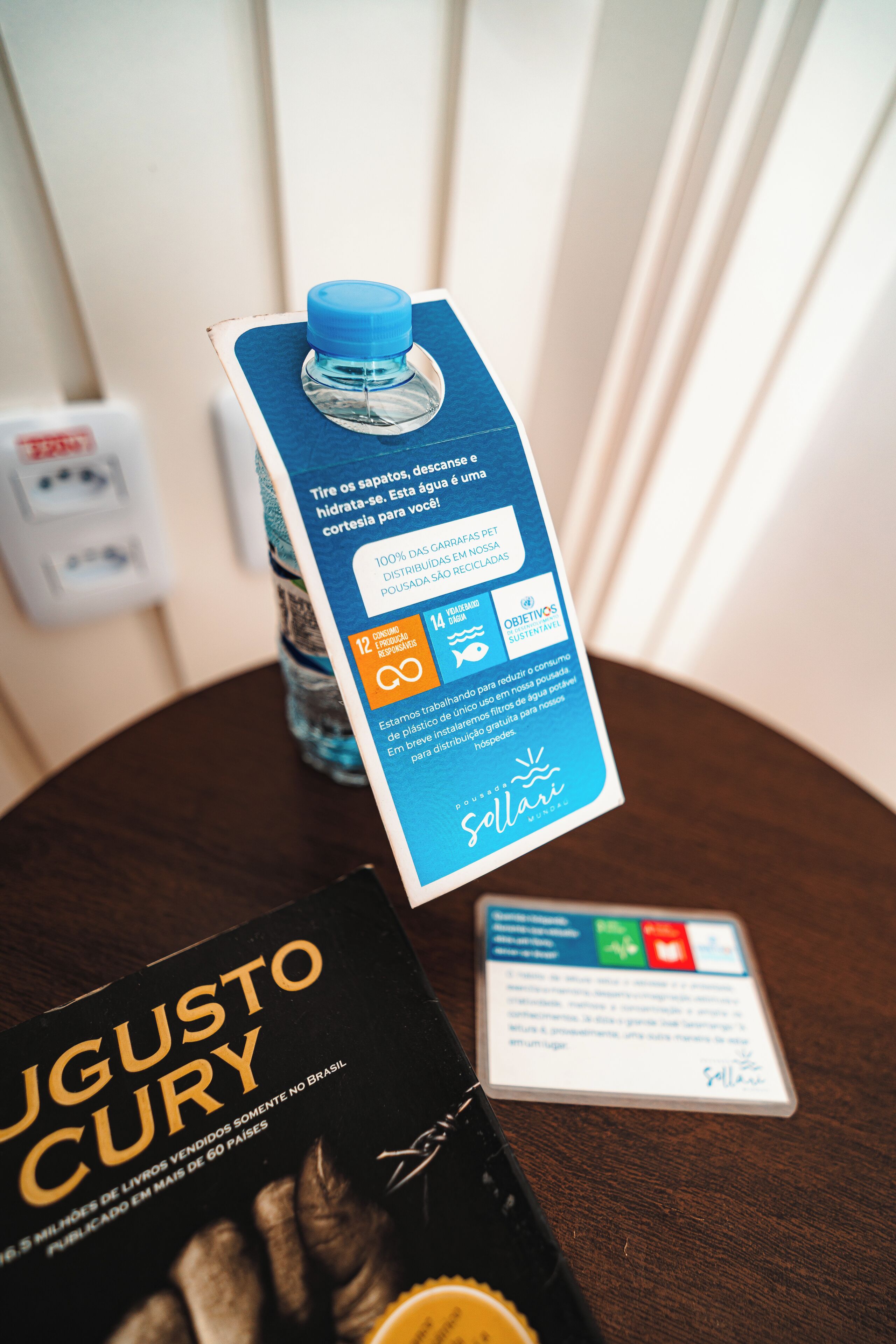 A book titled 'Augusto Cury' and a water bottle with a blue cap on a wooden table.