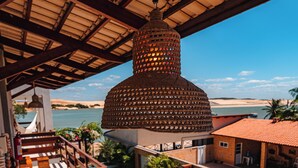 A rooftop terrace with a view of the sea, a wooden deck, and a large decorative structure. - POUSADA SOLLARI (Trairi)