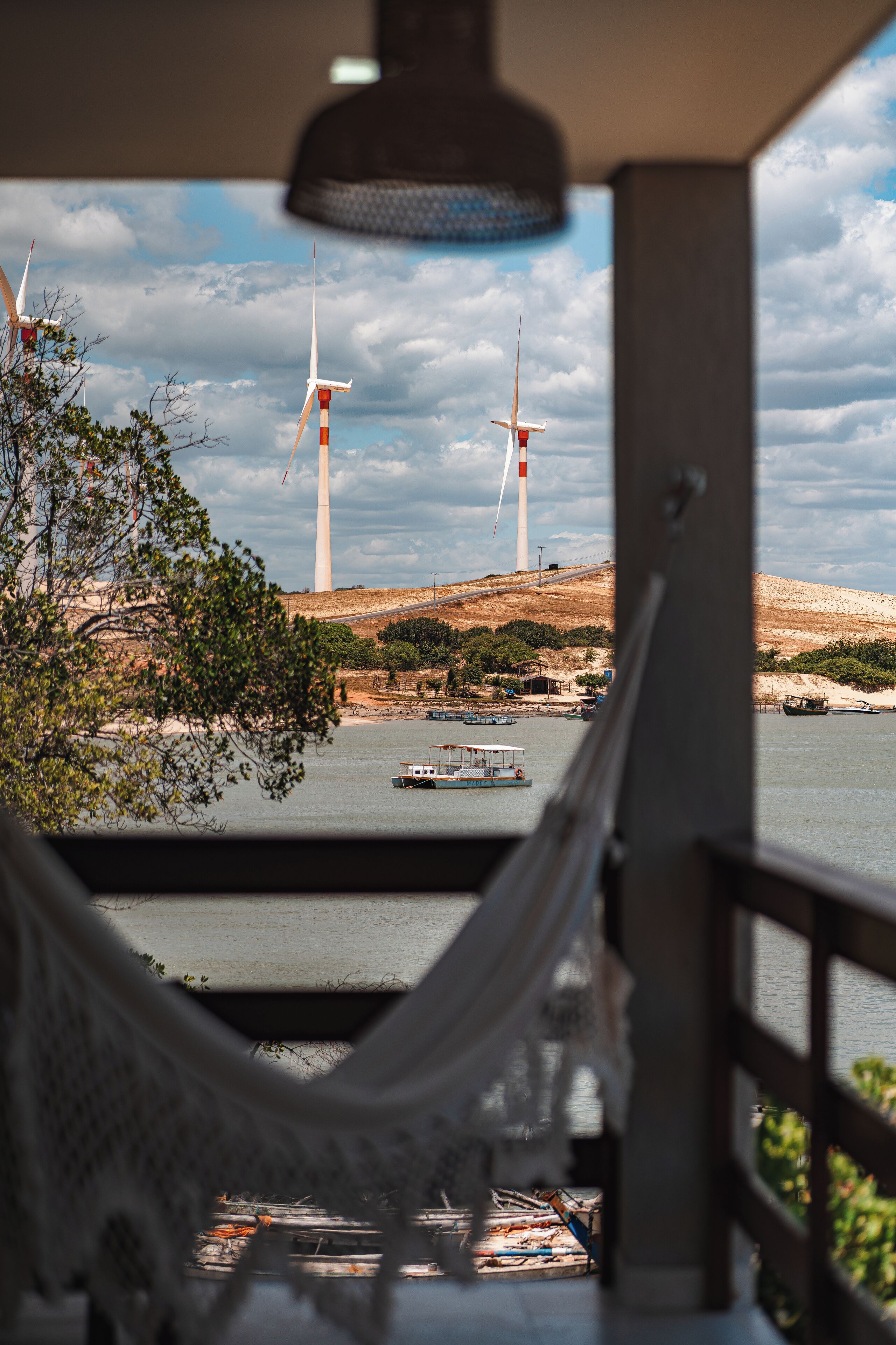 Un'amaca con vista su un fiume, sullo sfondo si vedono turbine eoliche.