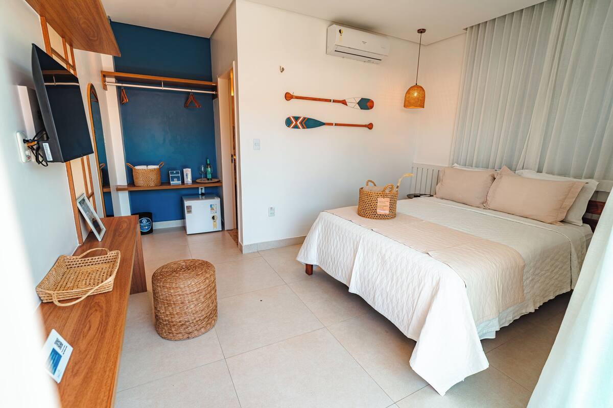 A bedroom with a bed, a desk, a chair, a basket, and a hanging paddle.