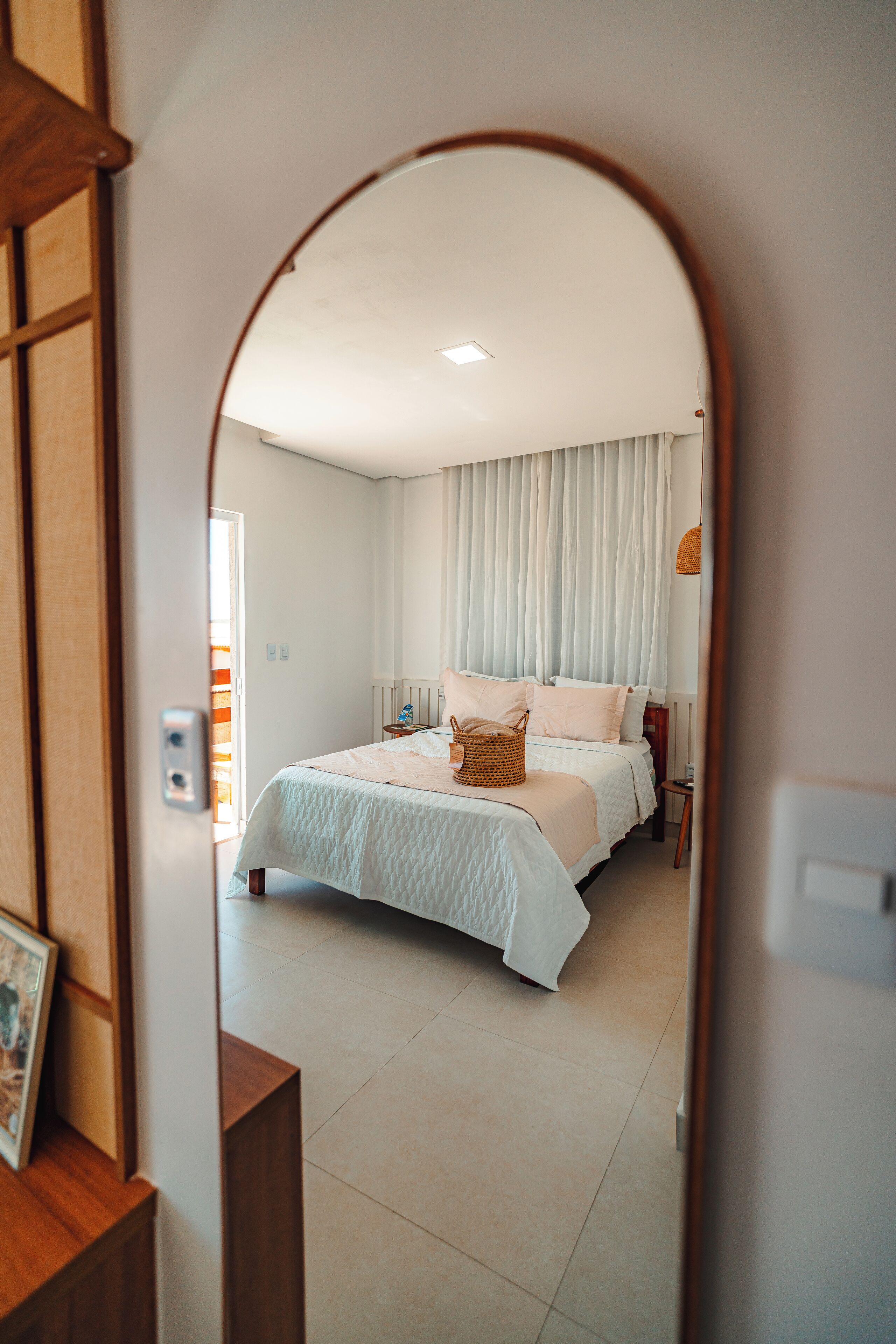 A bedroom with a bed, a bedside table, and a mirror.