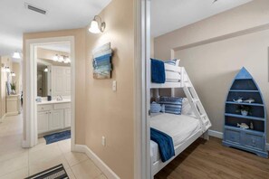 Ein Schlafzimmer mit Etagenbett, ein Badezimmer mit Waschbecken und eine Ablage mit Dekoration.