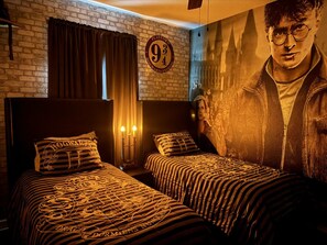 Ein Zimmer mit zwei Betten, einer Ziegelwand, einem großen Poster und einem Schild mit der Aufschrift 'Platform 9 3/4 Hogwarts Express'.