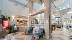 A spacious lobby with a high ceiling, wooden beams, and a seating area with blue upholstered chairs.