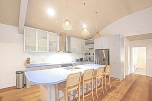 A modern kitchen with a central island, white cabinetry, and hanging pendant lights.