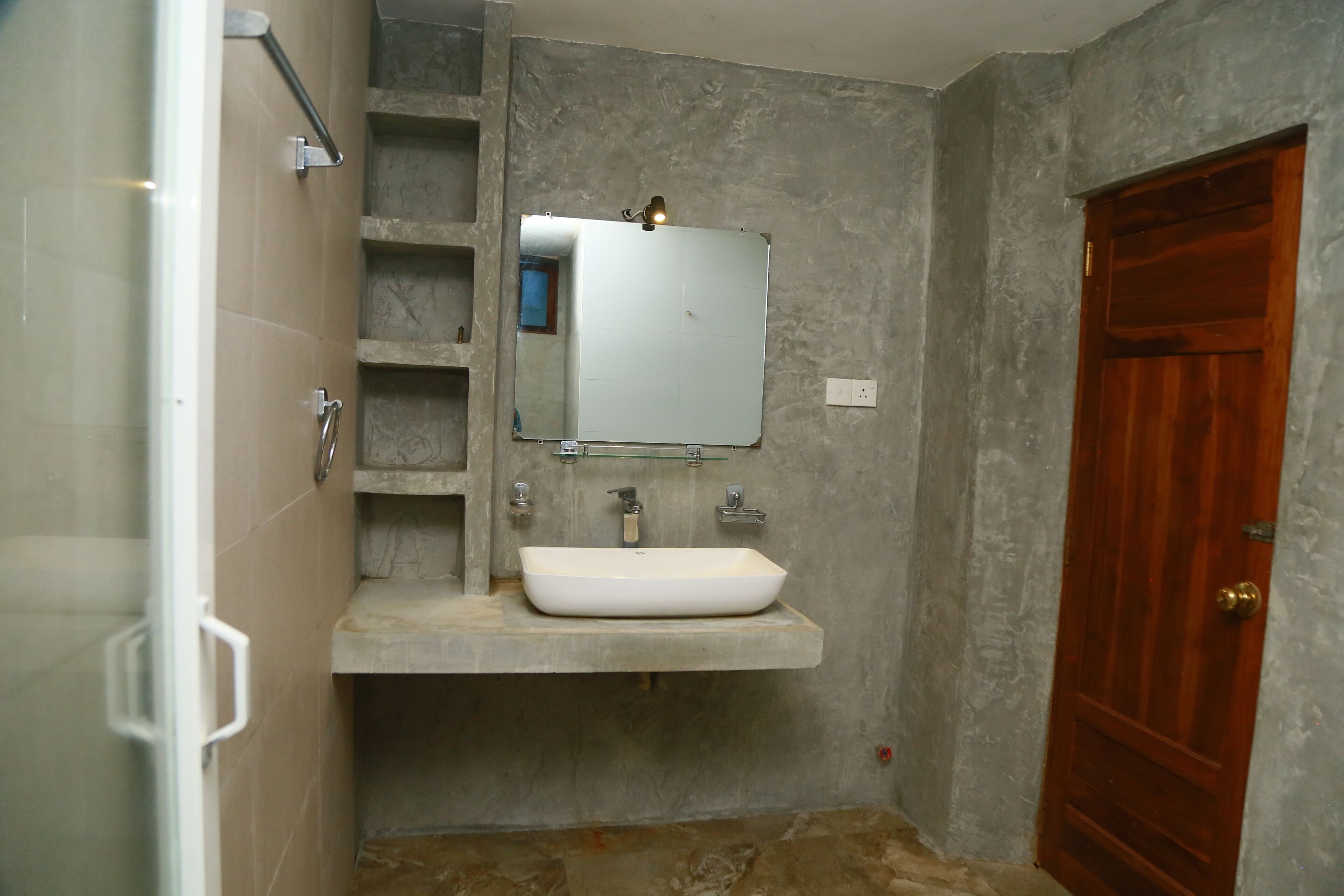 A bathroom with a white sink, a mirror, and a wooden door.
