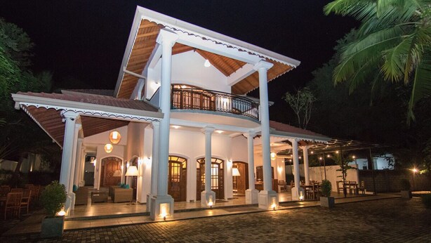 A two-story building with a balcony, multiple doors, and outdoor seating areas. - Adaviya Resort (Mahiyanganaya)
