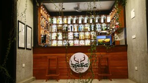 A bar area with shelves of liquor bottles, a wooden counter, and a sign for Adaviya Resort. - Adaviya Resort (Mahiyanganaya)
