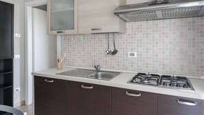 Une cuisine moderne dotée d’un évier en acier inoxydable, d’une cuisinière à gaz et d’armoires en bois.