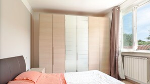 Une chambre à coucher avec un lit, une armoire et une fenêtre avec des rideaux.