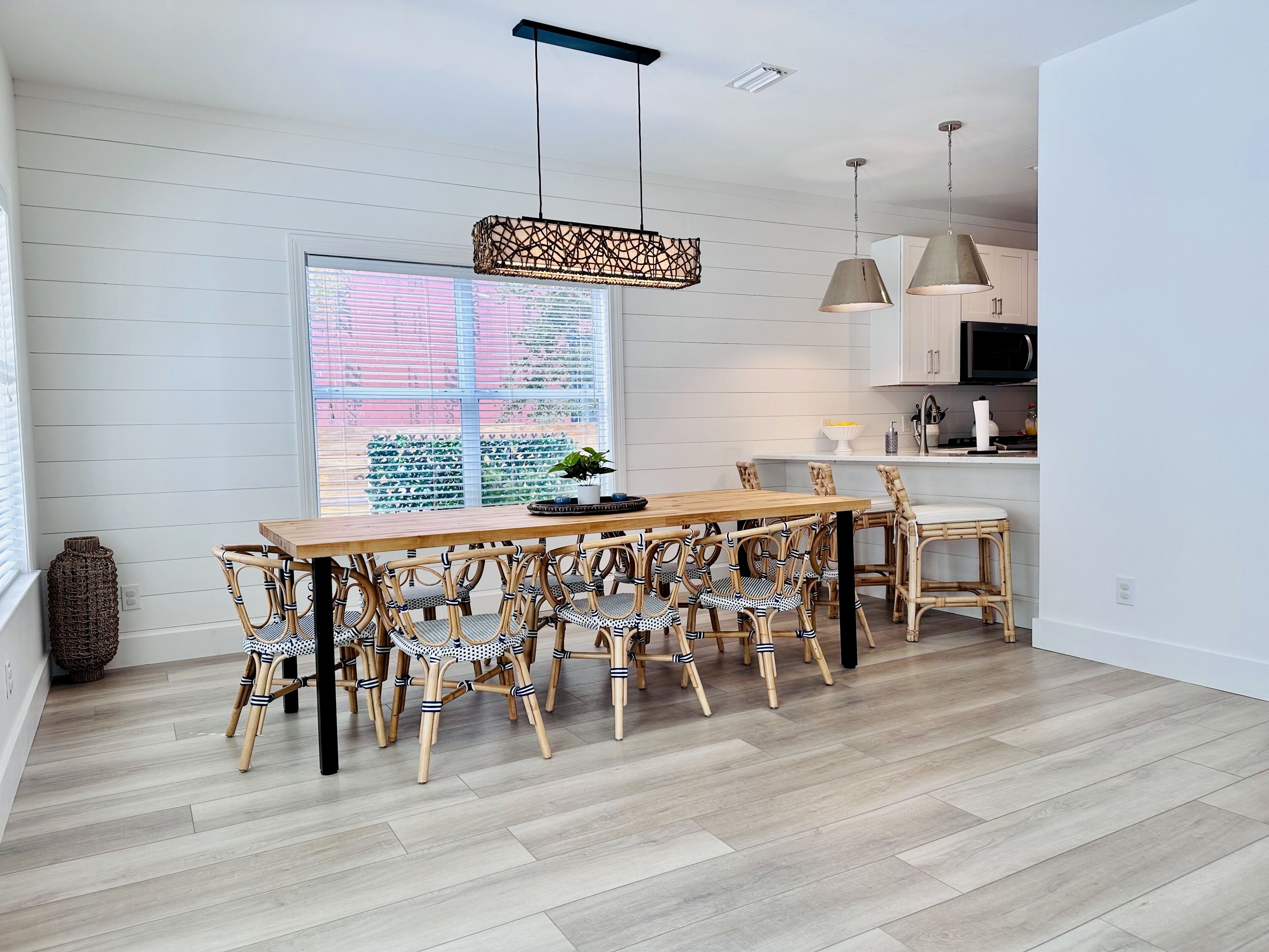 Una cocina moderna con armarios blancos, una mesa de comedor de madera y sillas de mimbre.