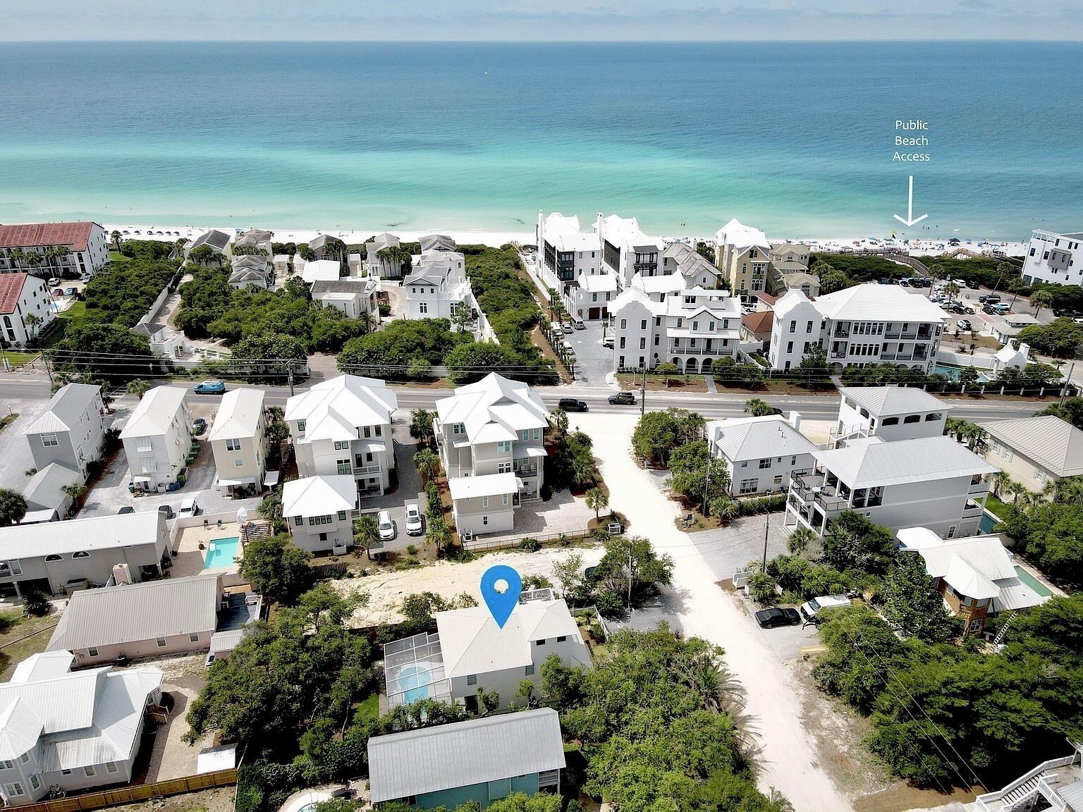 Una zona residencial costera con casas blancas, vista despejada a la playa y un lugar marcado.