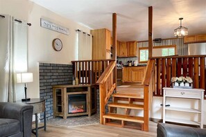 Ein gemütliches Wohnzimmer mit Kamin, einer Holztreppe und Blick ins Freie.