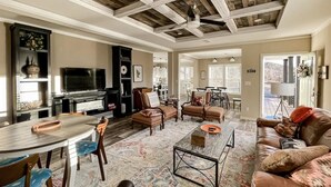 A spacious living area with a dining table, sofas, and a television.