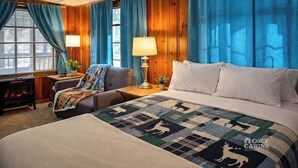 Quarto aconchegante com uma cama grande, uma cadeira, uma luminária e uma janela com cortinas.