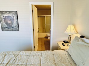 A hotel room with a bed, a bedside lamp, a remote control, and a painting on the wall. - Palm Paradise by Mesquite Vacation Rentals with Community Pool, Two Primary Suites and $510 in free daily activities (Mesquite)