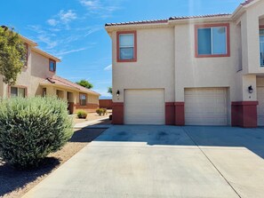 A residential building with two garages, a well-maintained driveway, and a small bush in the foreground. - Palm Paradise by Mesquite Vacation Rentals with Community Pool, Two Primary Suites and $510 in free daily activities (Mesquite)
