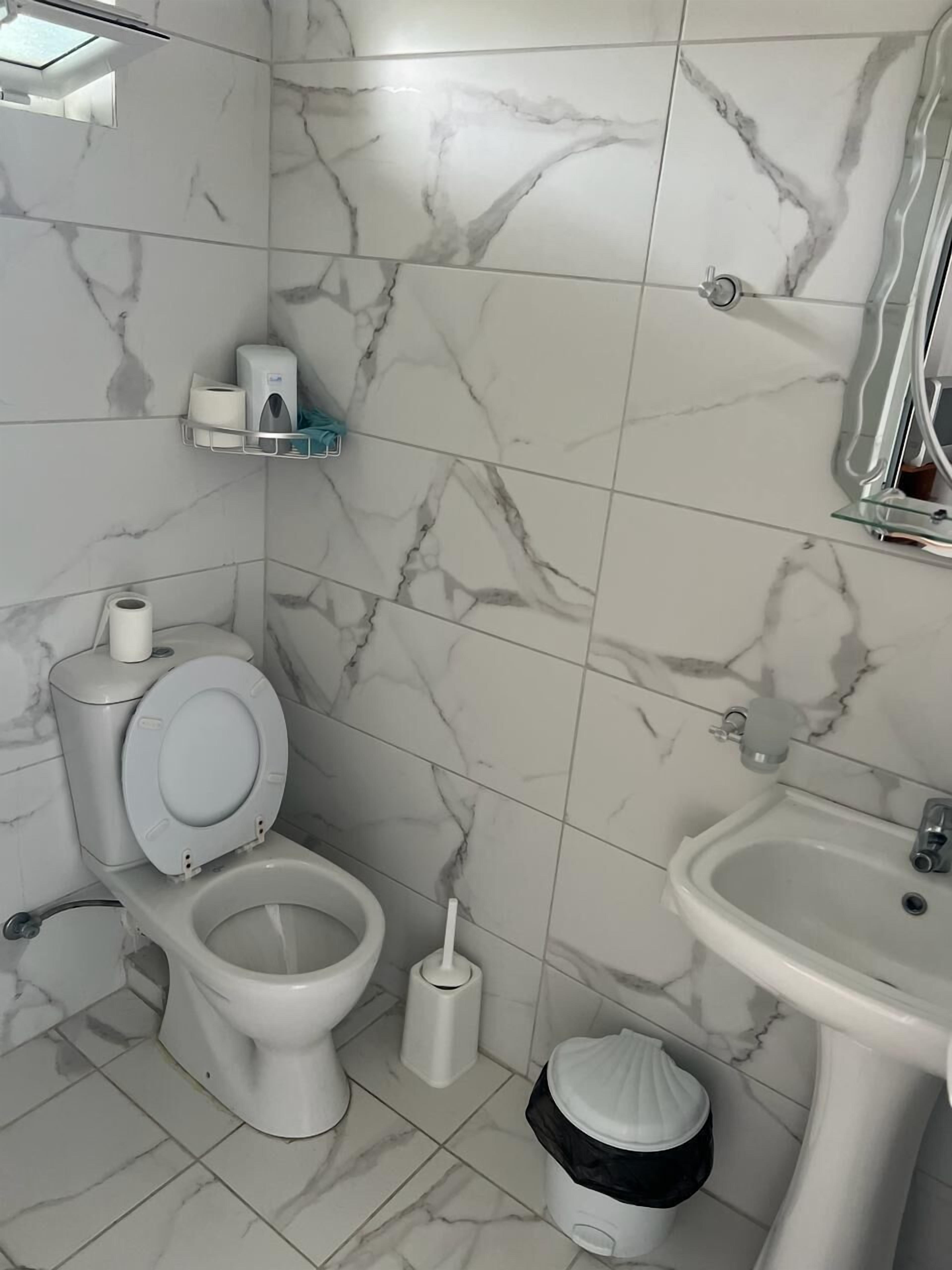 Une salle de bain avec des toilettes, un lavabo et des murs recouverts de carreaux de marbre.