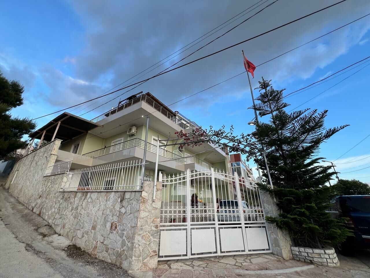 A two-story house with a stone facade, a balcony, and a gated entrance.