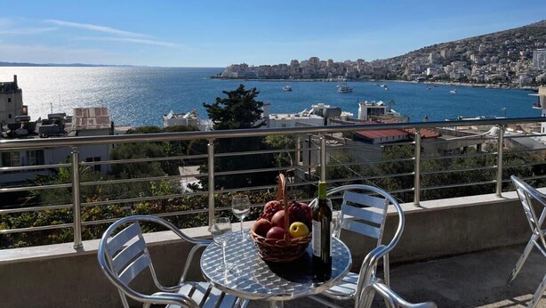 A balcony with a table, chairs, and a fruit basket with a bottle. - Villa AlMar (Sarandë)