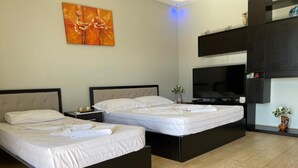 A modern hotel room with two beds, a flat-screen TV, and a decorative wall piece. - Villa AlMar (Sarandë)
