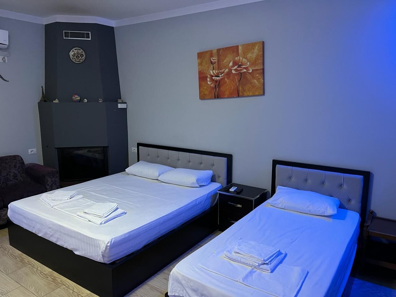 A hotel room with two beds, a flat-screen TV, a fireplace, and a painting on the wall.