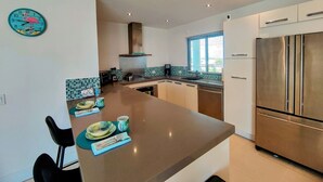 Una cocina moderna con una isla central, electrodomésticos de acero inoxidable y un reloj decorativo en la pared.