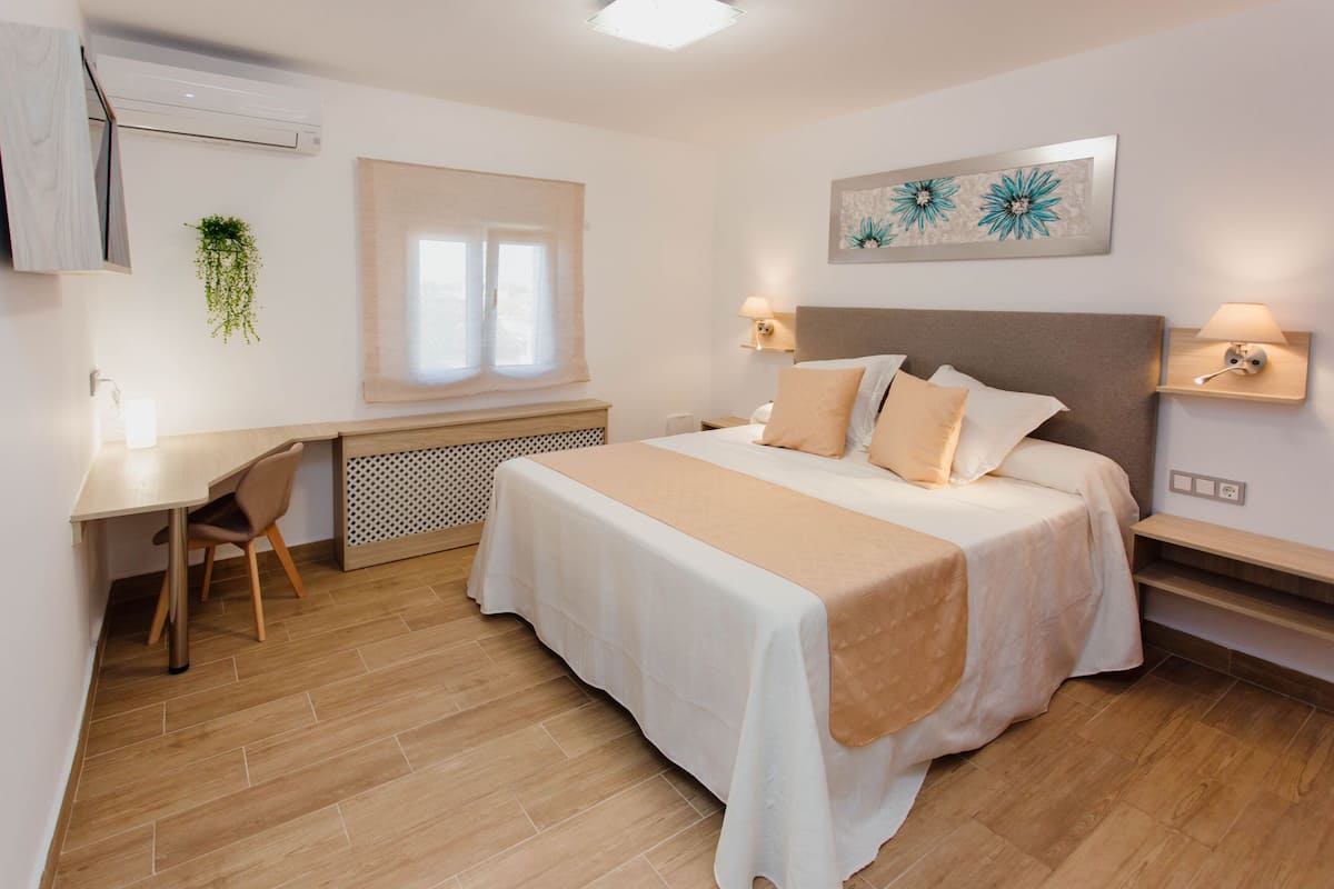 Une chambre à coucher avec un lit, des tables de chevet, un bureau et une chaise.