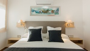 Habitación de hotel con una cama, dos mesitas de noche, dos lámparas de pared y una obra de arte enmarcada sobre la cama.