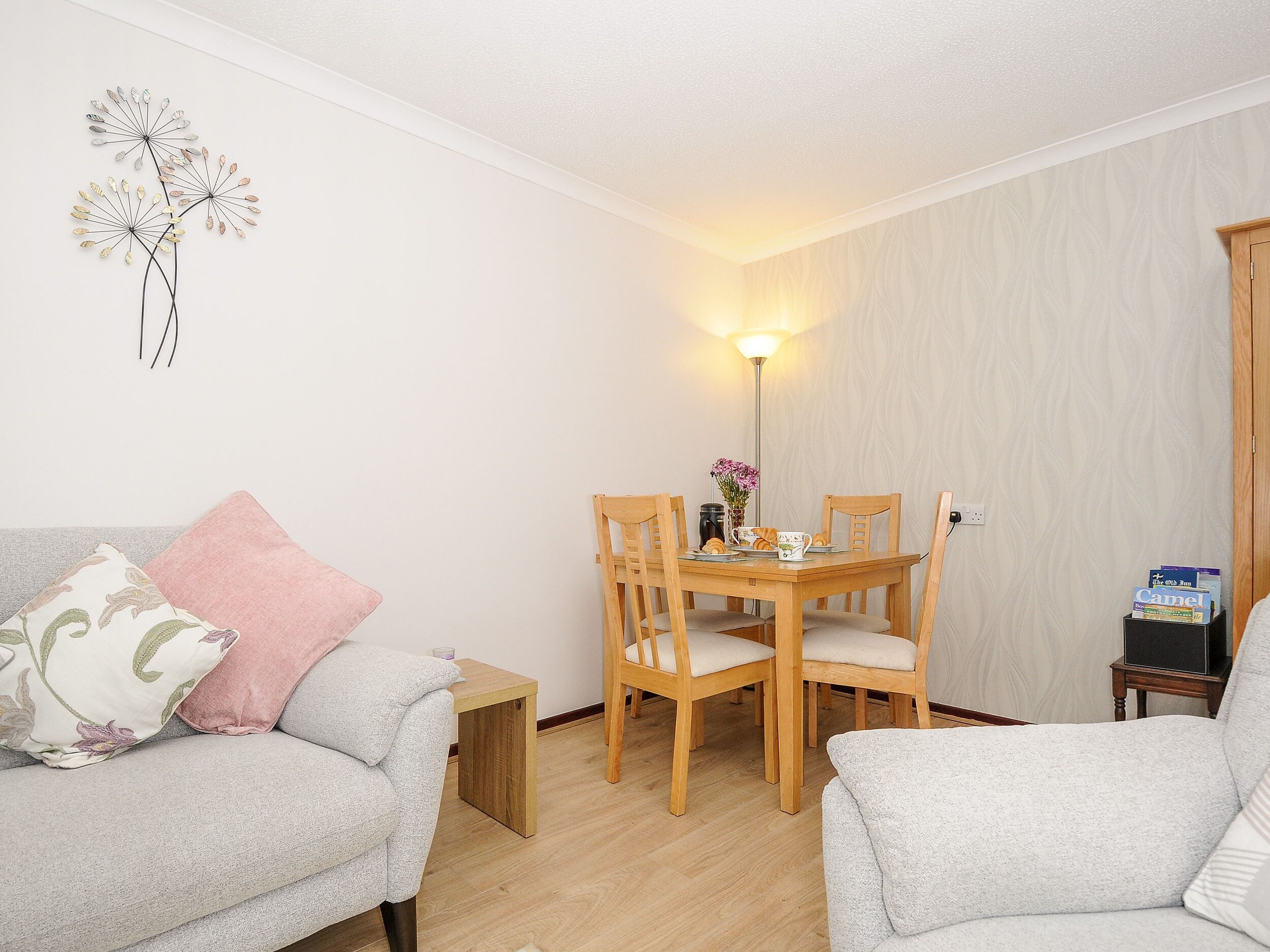A cozy living room with a sofa, a dining table with chairs, and a small side table.