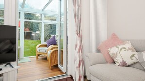 Una sala de estar con televisión, sofá y puerta de vidrio que da a un jardín.